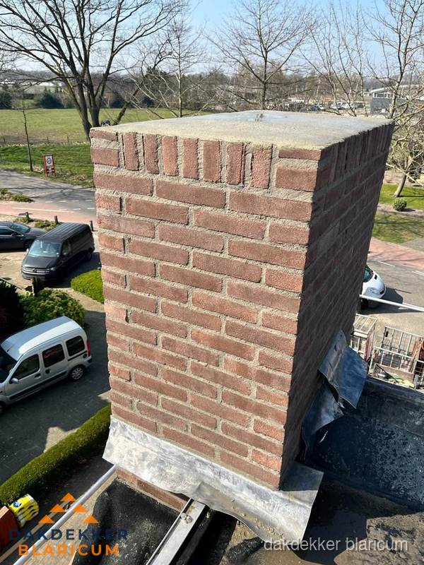 Gemetselde schoorsteen met loodaansluiting op dak in Blaricum