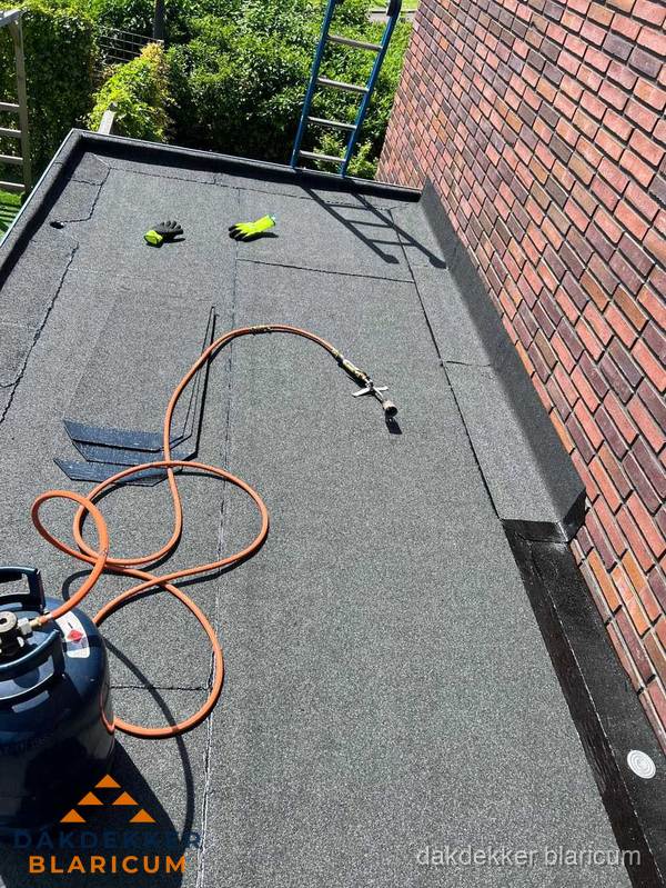 Plat dak met bitumen en brandgereedschap van dakdekkersbedrijf in Blaricum