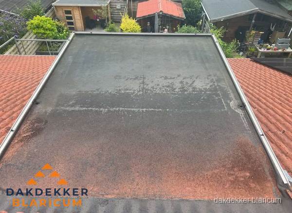 Verouderd plat dak met slijtage tussen schuine daken in Blaricum