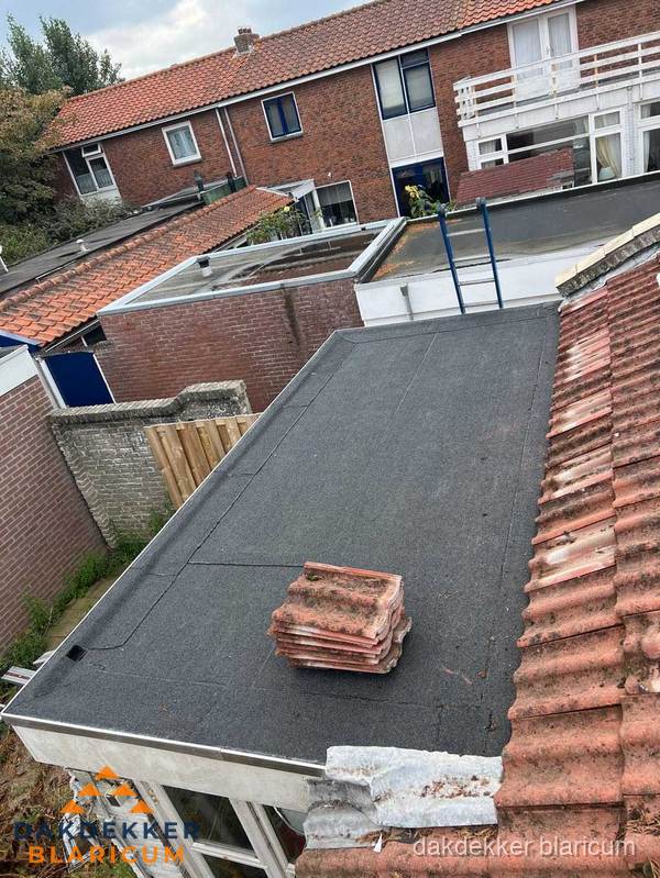 Plat dak aanbouw met bitumen naast schuin pannendak in Blaricum