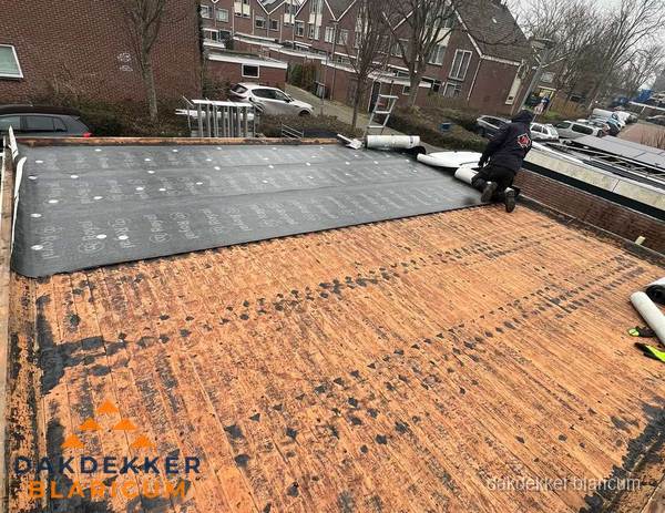 Dakdekker legt onderlaag op plat dak met houten constructie in Blaricum
