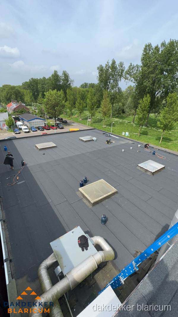 Dakdekker aan het werk op groot plat dak met bitumen in Blaricum